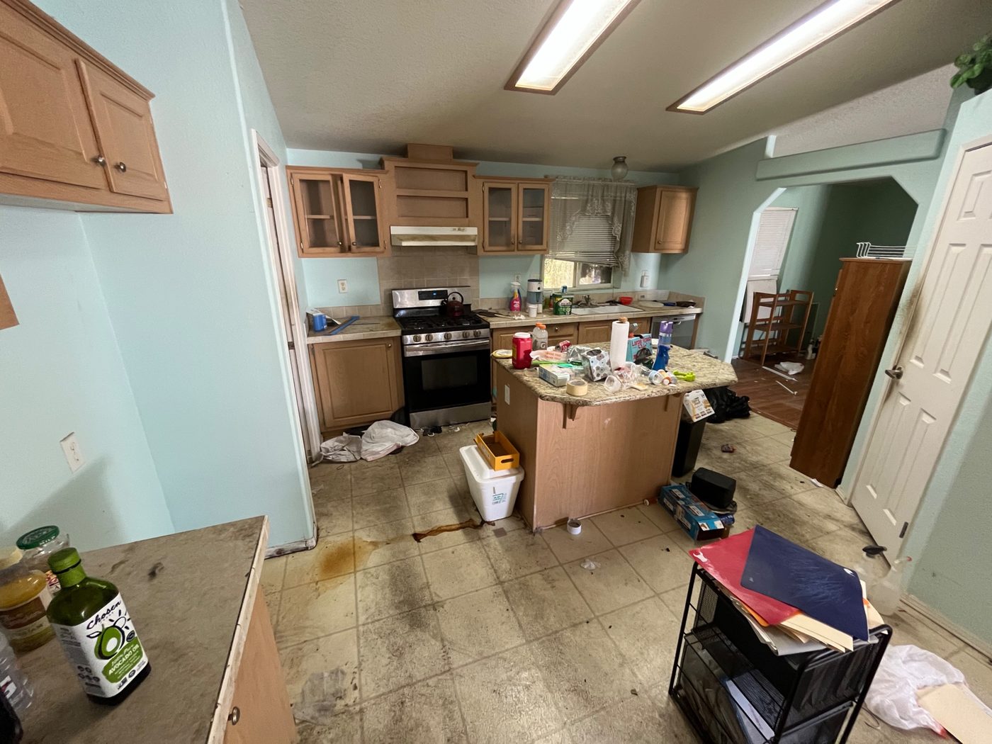 Mobile home kitchen with heavy staining and mess on the floor, purchased as-is by Infinite Legacy Property Solutions